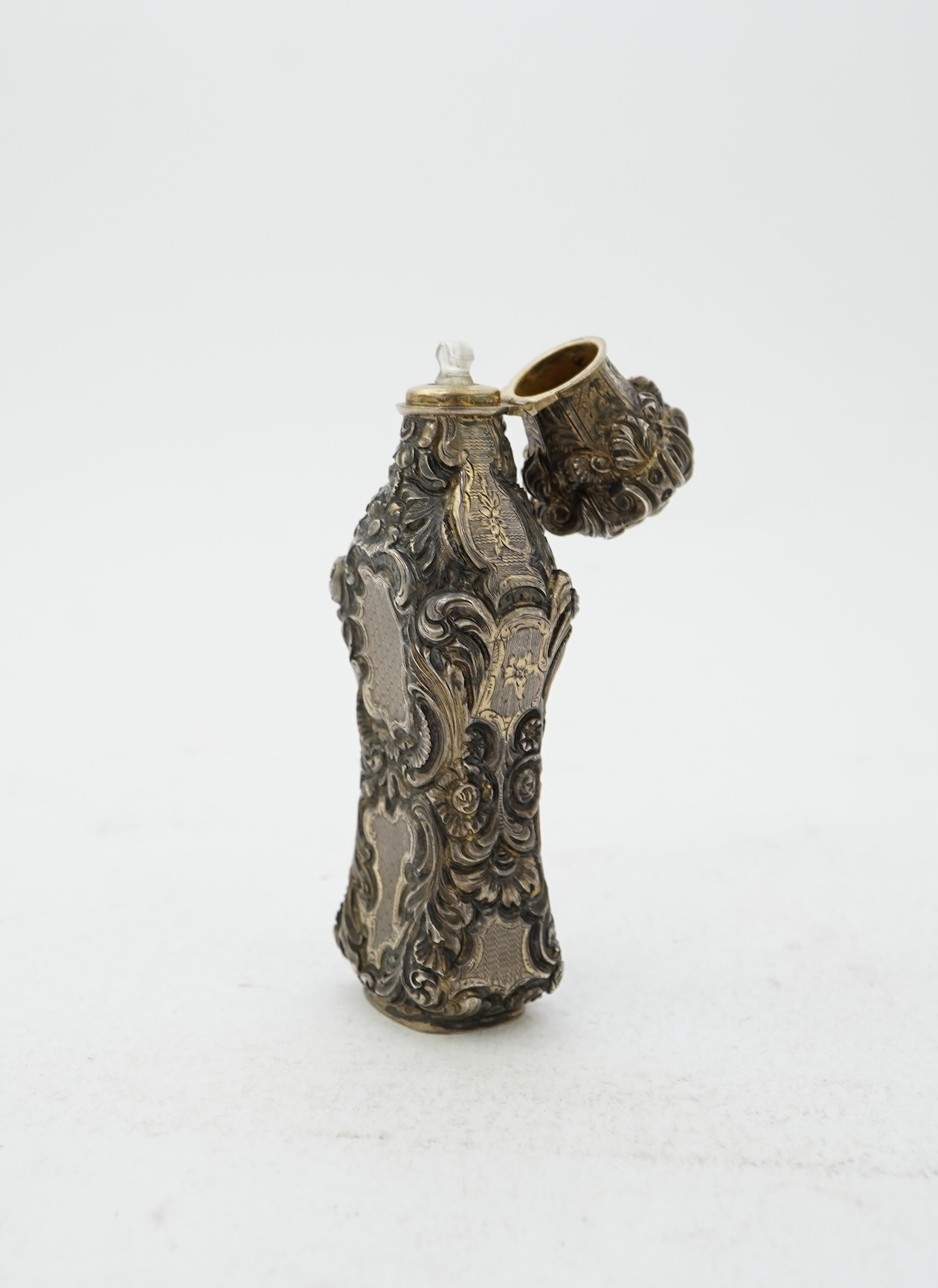 A 19th century French ornate parcel gilt white metal scent flask, with hinged cover and glass stopper